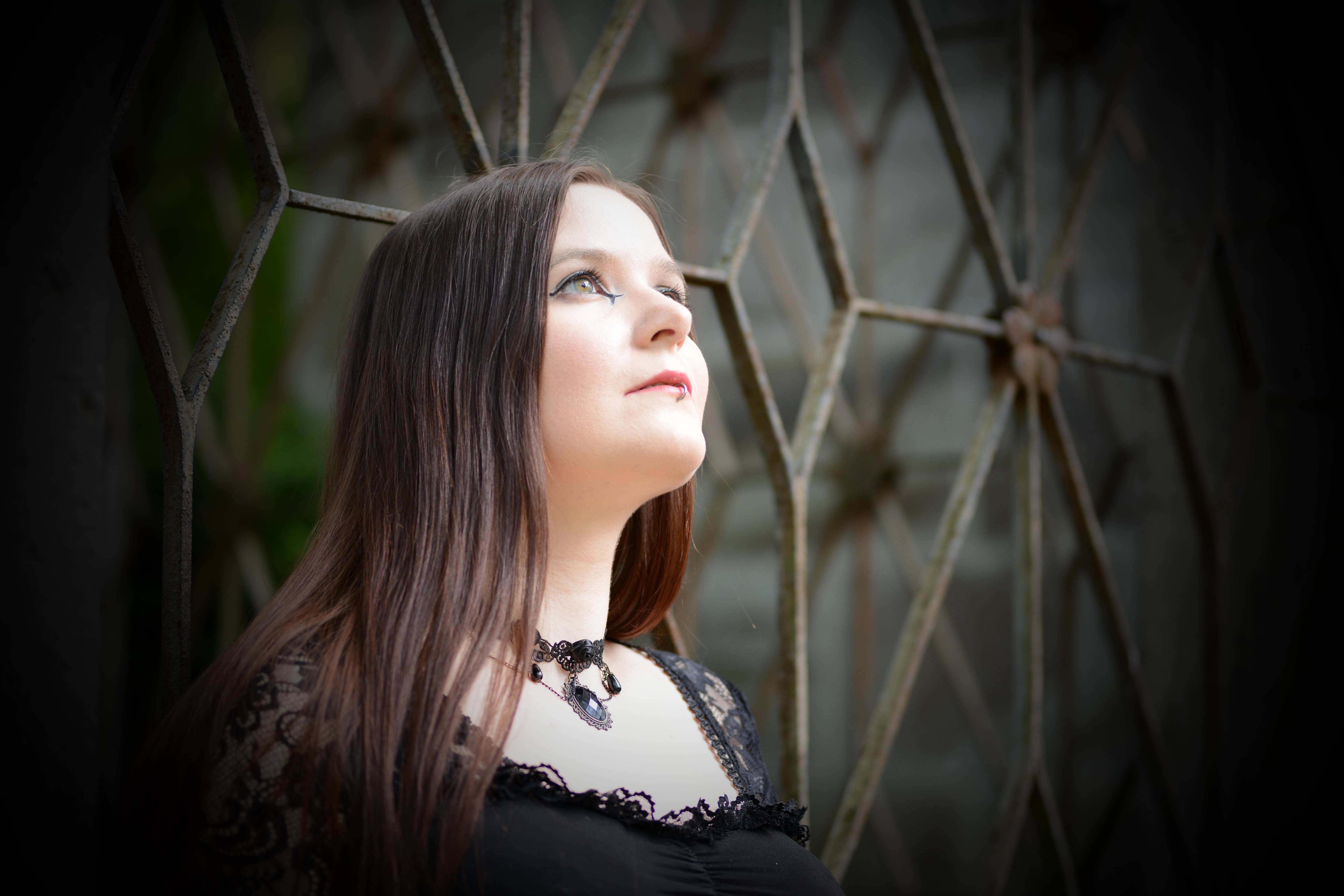 Mélanin im Gothic-Stil an einem leicht zerfallenen Metallzaun lehnend in den Melaten in Köln